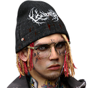 A man with a black beanie, red-streaked hair, and facial tattoos looking directly ahead with a serious expression.