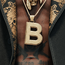 A gold letter B pendant hangs from a chain against a dark, patterned shirt.