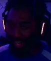 A man wearing headphones with a shocked expression in a dimly lit, blue-toned room.