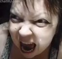 A person with a wide-eyed, distorted face screaming with their mouth open wide.