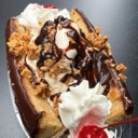 Banana split sundae topped with whipped cream, chocolate sauce, and a bright red cherry.