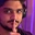 A man with a mustache making a shh gesture by holding his finger to his lips.