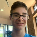 A young person with glasses smiling in a casual, close-up selfie.