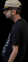A man in a baseball cap stands in profile with a slouching, unimpressed posture against a black background.