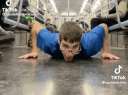 A man in a blue shirt lies on a subway floor and licks the ground in a four-part sequence.