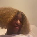 Person with curly hair looking down at the camera with a skeptical and unimpressed expression.