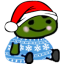 A small green creature wearing a red Santa hat and a blue snowflake sweater sits calmly.