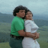 A man and a woman in a romantic embrace against a hilly landscape background.