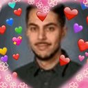 A man looking at the camera, framed by a pink heart-shaped border filled with various colorful heart emojis.