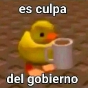 A small yellow 3D duck holding a white coffee mug with the text es culpa del gobierno written above and below it.