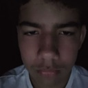 Young man staring with a deadpan, unimpressed expression in low lighting.