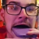A person wearing glasses with a purple smartphone held firmly between their teeth.