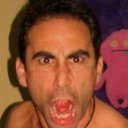 Man with wide eyes and mouth open in a loud, intense scream.