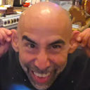 Bald man pulling his ears outward with a wide, silly grin.
