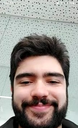 Man with a dark beard and hair smirking at the camera.