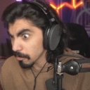 A man with a mustache and headphones looking at the camera with wide, shocked eyes.