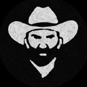 Cowboy with a beard and hat staring forward with a serious expression.
