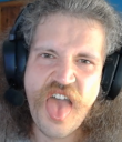 Man wearing headphones sticking his tongue out in a playful, goofy expression.