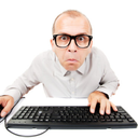 A man wearing glasses looking intensely at a keyboard with a frustrated expression.