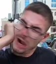Man wearing glasses clutching his face with his hand in a dramatic reaction to being slapped.