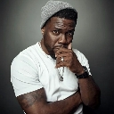 Kevin Hart looking suspicious with his hand near his mouth.