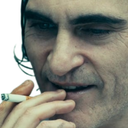 A man with a cynical smirk holding a cigarette between his fingers.