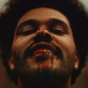 The Weeknd with a bloodied face and a smirk looking directly into the camera.