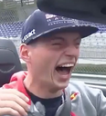 A man wearing a baseball cap with his mouth wide open in a loud, joyful laugh.