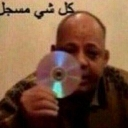 A man holding a CD in front of his face with Arabic text above him.