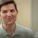 Adam Scott looking excited while holding up a plastic food container.