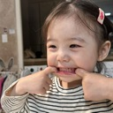 Toddler pulling their cheeks to make a wide, silly, toothy grin.