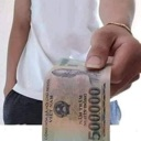 A person's hand holding out a 500,000 Vietnamese Dong banknote.