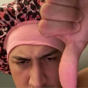 Person wearing a leopard-print bonnet giving a dramatic thumbs down gesture.