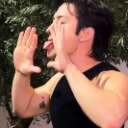 Chase Hudson making a silly face with his tongue sticking out and hands framing his face.