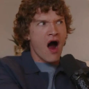 Man with curly hair making a dramatic, wide-mouthed expression of shock.