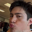 A man looking directly at the camera with his lips puckered in an exaggerated kissy face expression.