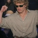 Derek Zoolander wearing sunglasses dancing enthusiastically with his arms raised.