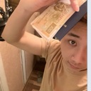 A person holding a stack of cash up to the camera with a smug expression.