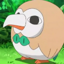 A round brown and white bird with a green bowtie stares blankly with a large beak.