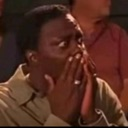 Man with a shocked expression covering his mouth with both hands.