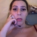 A young woman looking directly at the camera with a confused and skeptical expression while resting her hand near her face.