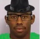 Tyler the Creator wearing a black fedora and glasses looking directly at the camera.