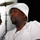Man wearing a white bucket hat looking sideways with a skeptical and judgmental expression.