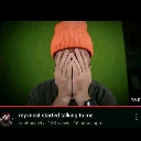 Person wearing an orange beanie covering their face with both hands in a gesture of frustration.