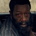Man with a beard looking directly at the camera with wide, weary eyes expressing deep shock.