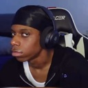 A man wearing a durag and headphones stares into the camera with a deadpan, unimpressed expression.