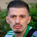 Man with a mustache stares directly forward with a serious and unimpressed facial expression.