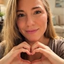Woman smiling while making a heart shape with her hands.