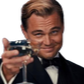 Leonardo DiCaprio in a tuxedo smiling and raising a glass in a toast.