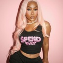 Woman with long pink hair wearing a black crop top posing confidently.